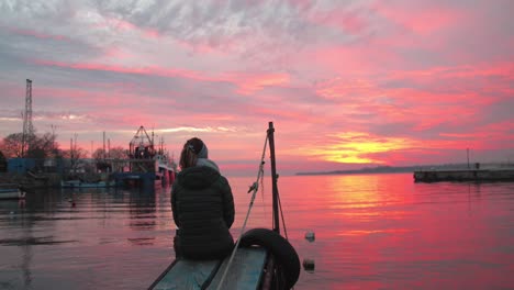 Woman-Watching-The-Beautiful-Sunset-While-Sitting-At-The-Sea-Port-In-Bulgaria---wide-shot