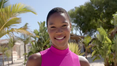 Portrait-of-happy-african-american-woman-looking-at-camera-at-beach-house