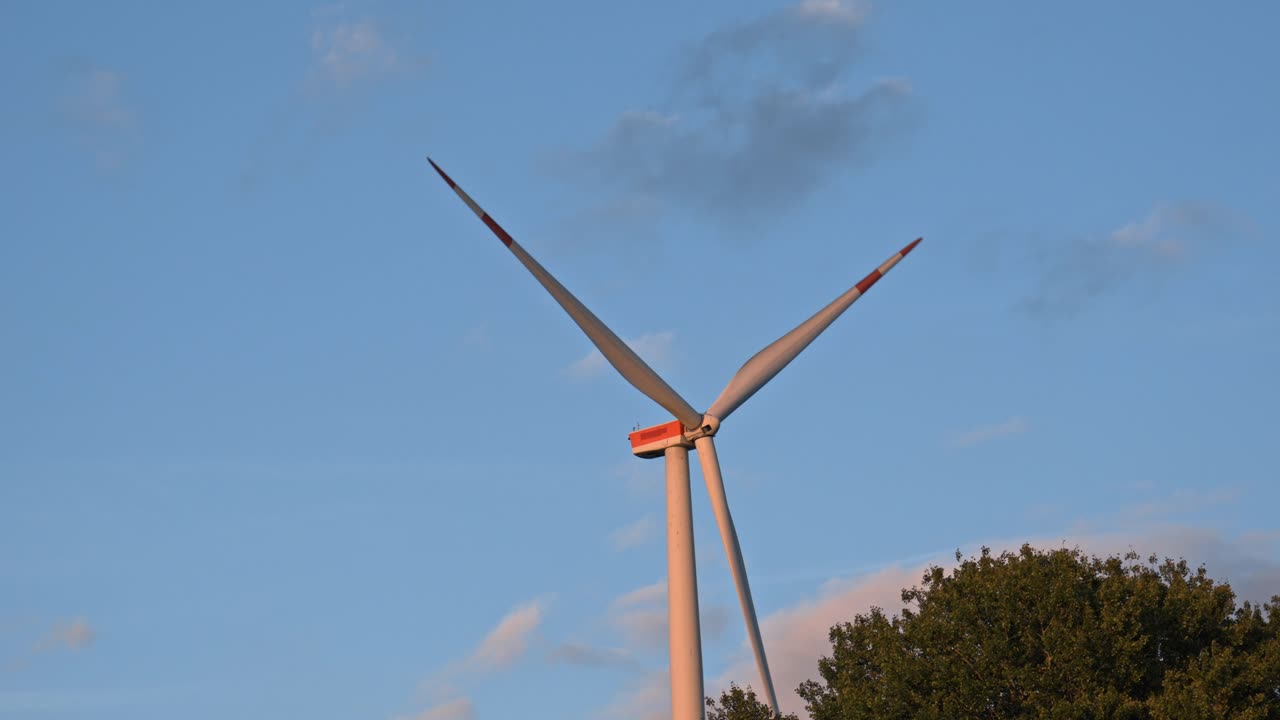 A modern onshore wind turbine silhouetted against a colorful, darkening sky at dusk in Germany