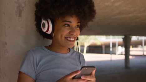 mixed race woman listening music under bridge