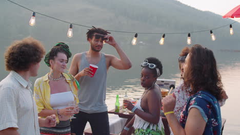 young people dancing on pier at lake party