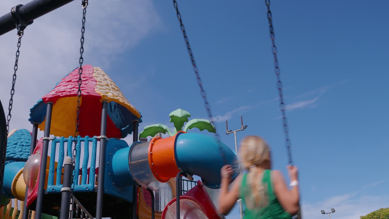 niño balanceándose alto en el patio de recreo colorido