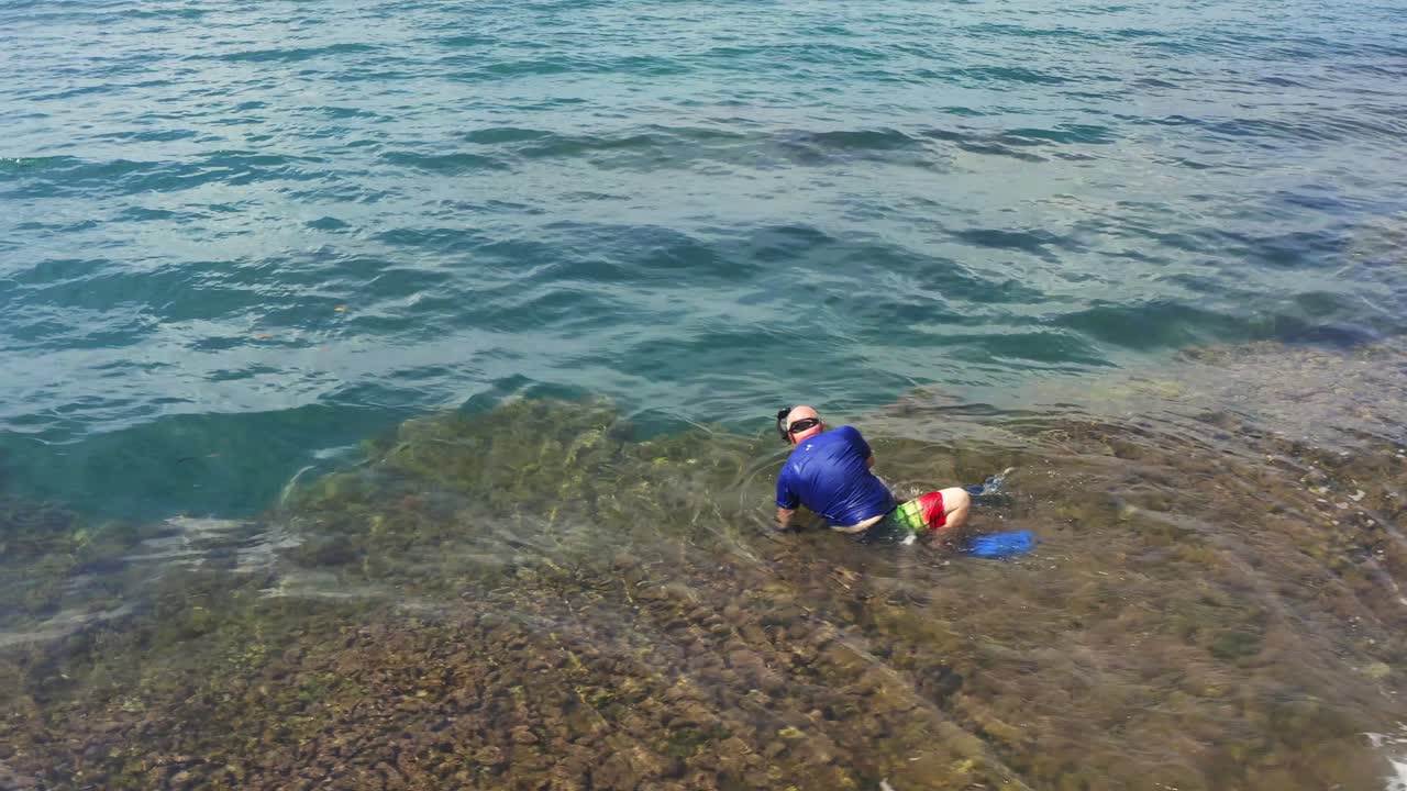 파나마 해안선에서 산호초 바다 물에 들어가기 위해 고군분투하는 스노클 다이버의 공중 전망