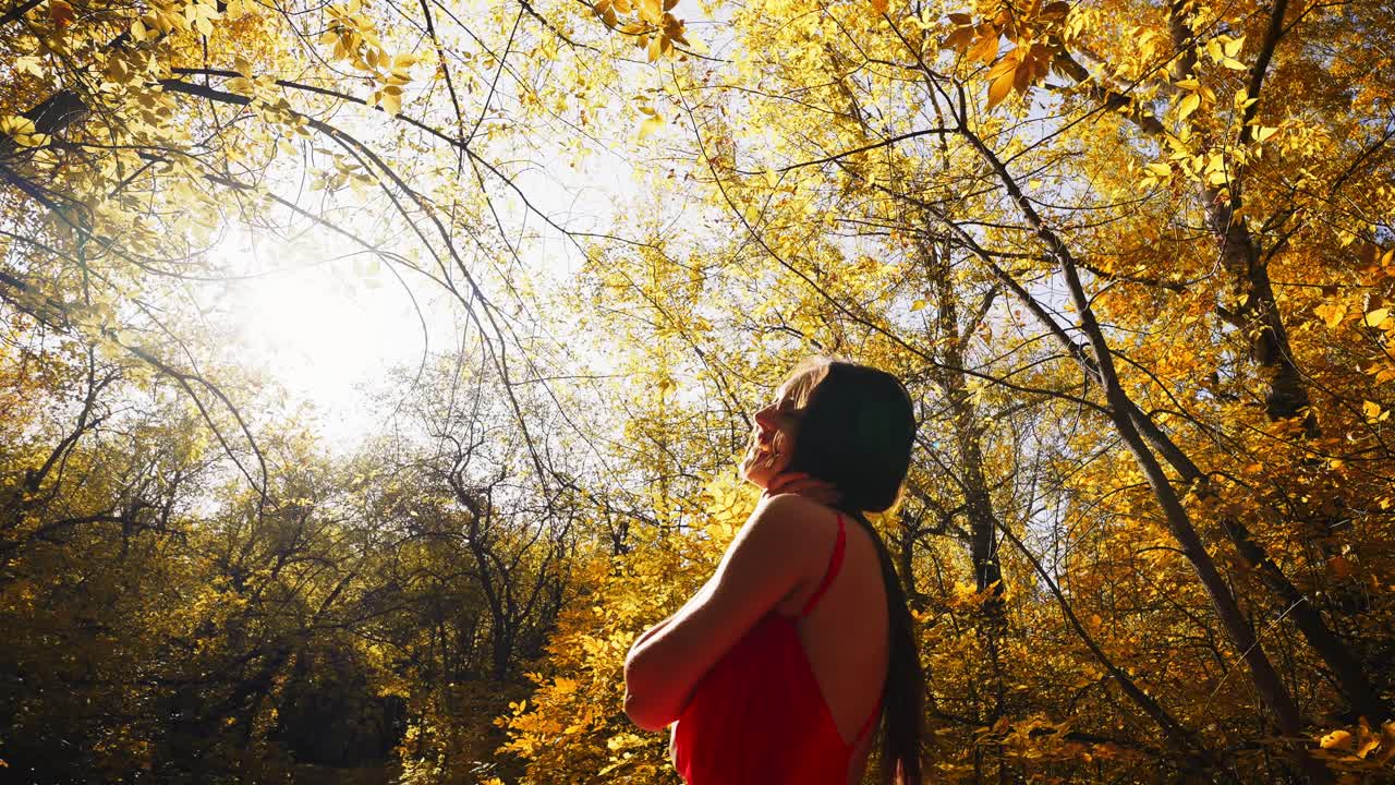 A serene moment captured in a sunlit forest, showcasing a figure in a red dress surrounded by vibrant autumn leaves, embodying tranquility and connection with nature