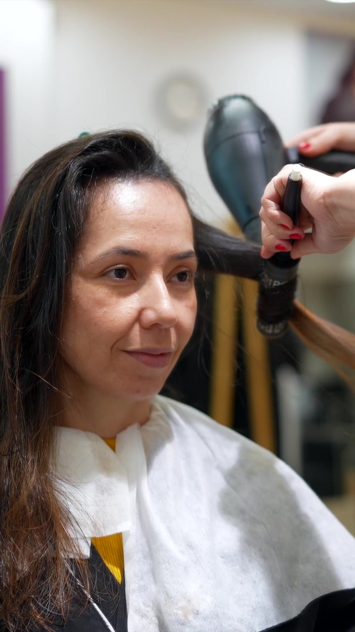 Estilista profesional secando el cabello de un cliente con secador en un salón