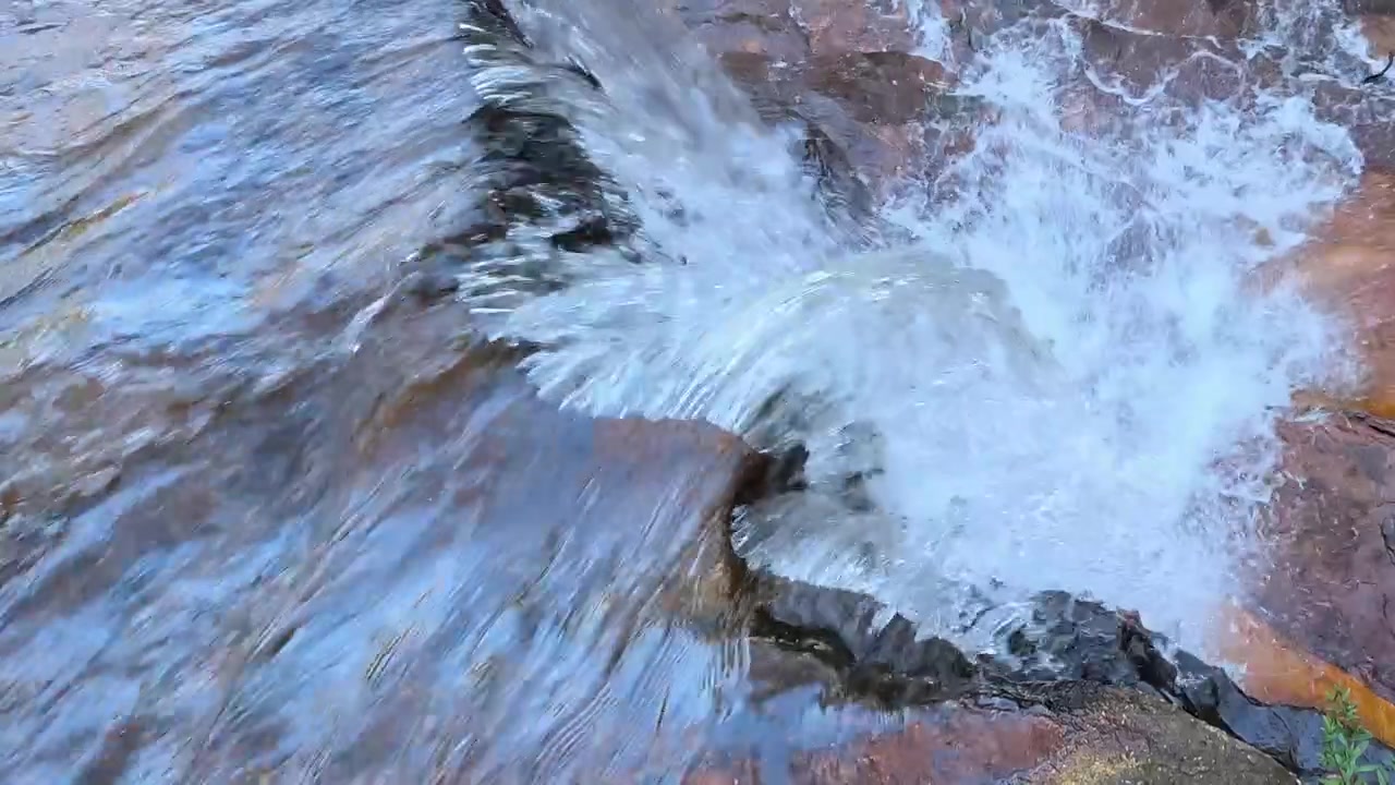 Close-up of rushing water flowing over a sandstone cliff edge in Blue Mountains, Australia.