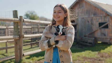 happy girl holding adorable baby goat on a farm