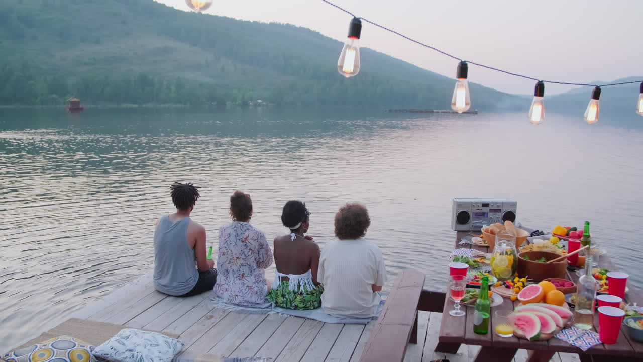 Friends Sitting on Wooden Pier at Lake Party