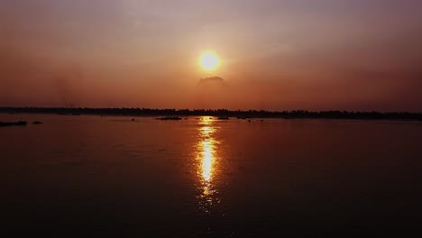 glorious sunset in cambodia reflecting on the waters of mekong river - beautiful scenery - tilt up shot