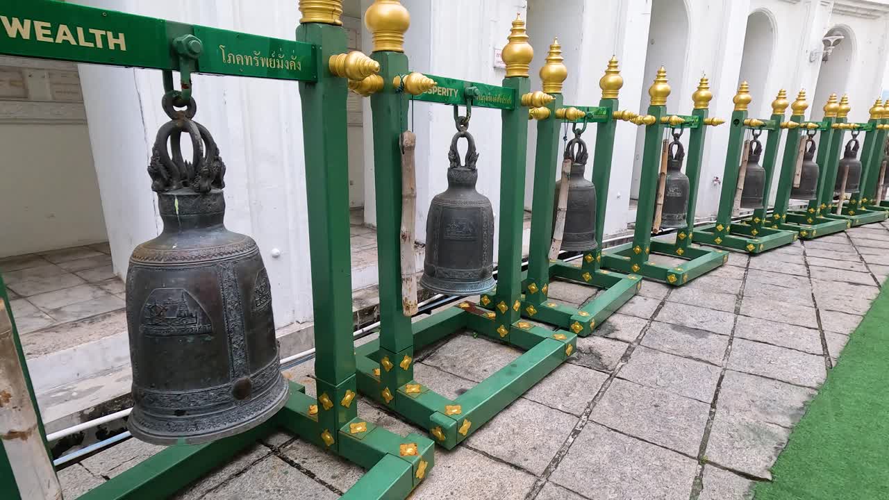 A series of bronze bells aligned in a temple courtyard, captured in natural daylight with a focus on cultural significance