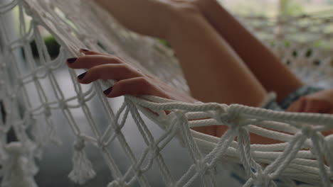 close up hand of woman in hammock gently moving fingers sleeping comfortable on holiday in vacation resort swaying peacefully on lazy summer day