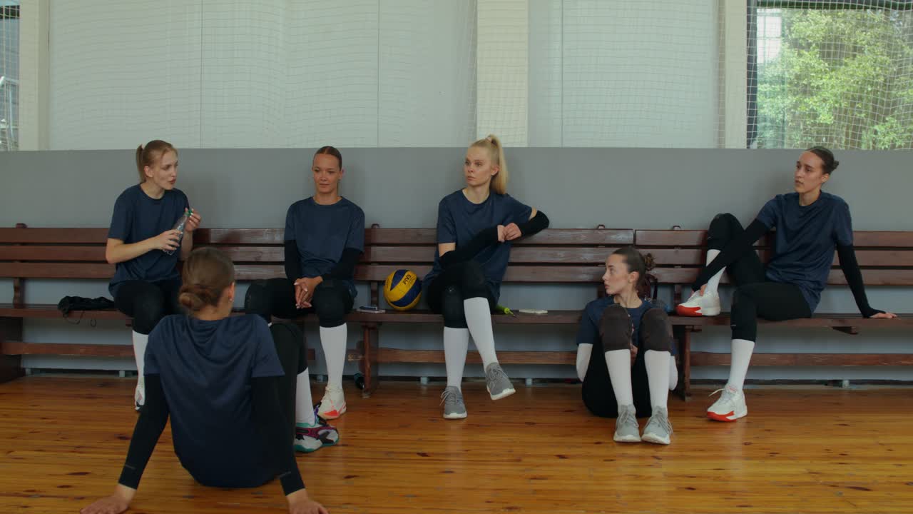 Una squadra di pallavolo seduta su una panchina al chiuso