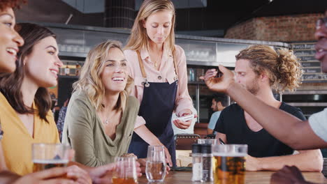 customer making contactless payment on mobile phone to waitress for meal in restaurant