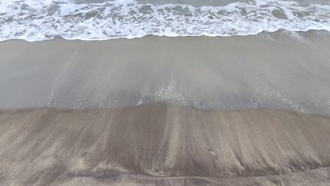 Zeitlupenansicht-Von-Strandwellen,-Die-Sich-An-Einem-Schwarzen-Sandstrand-Kräuseln