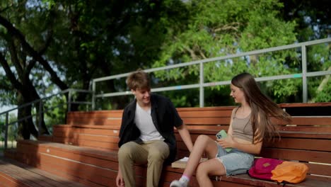 una pareja joven sentada en un banco en un parque, sonriendo y pareciendo feliz.