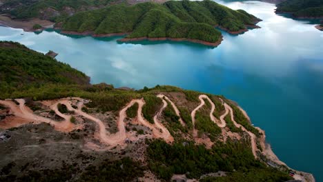 Aerial-of-hair-pin-road-towards-top-of-rock-and-view-of-Lake-Bovilla-in-Albania