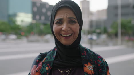 Retrato-De-Una-Elegante-Mujer-Musulmana-Madura-Riendo-Alegre-Mirando-La-Cámara-Feliz-Disfrutando-Del-Estilo-De-Vida-Urbano-Usando-El-Tradicional-Pañuelo-Hajib