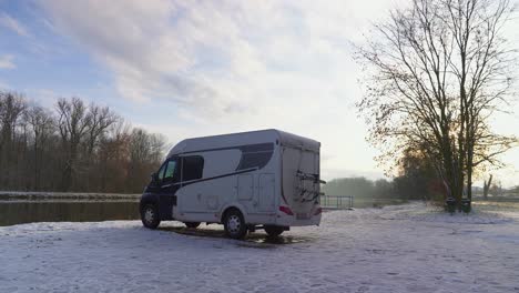 rv parked on the river bank during sunny winter weather