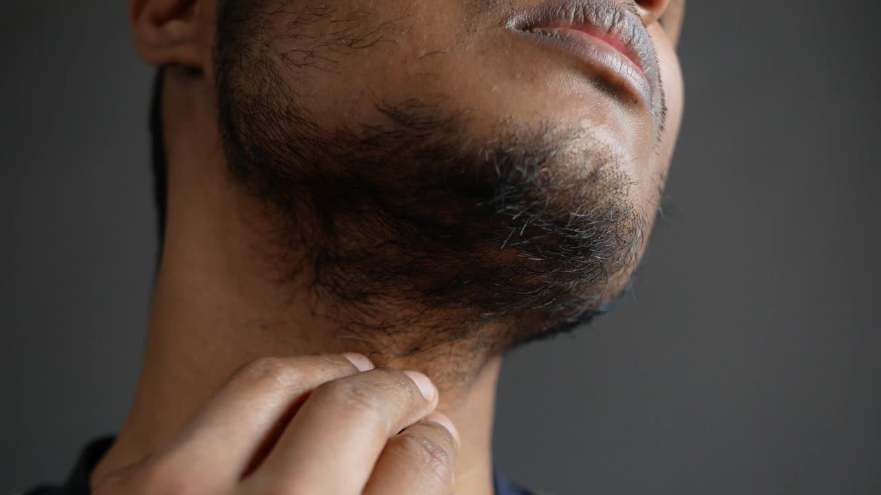 Uomo che si gratta il collo con la barba