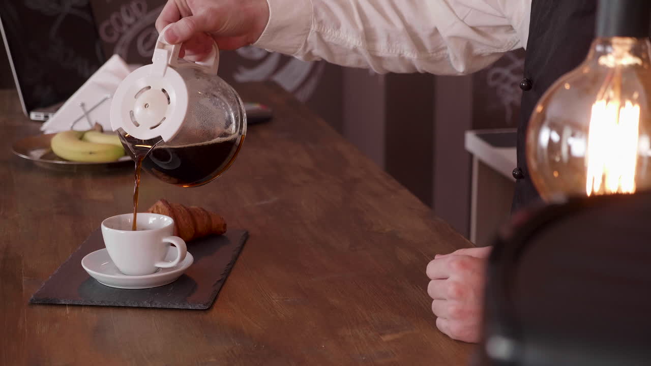 Pouring coffee with croissant on table