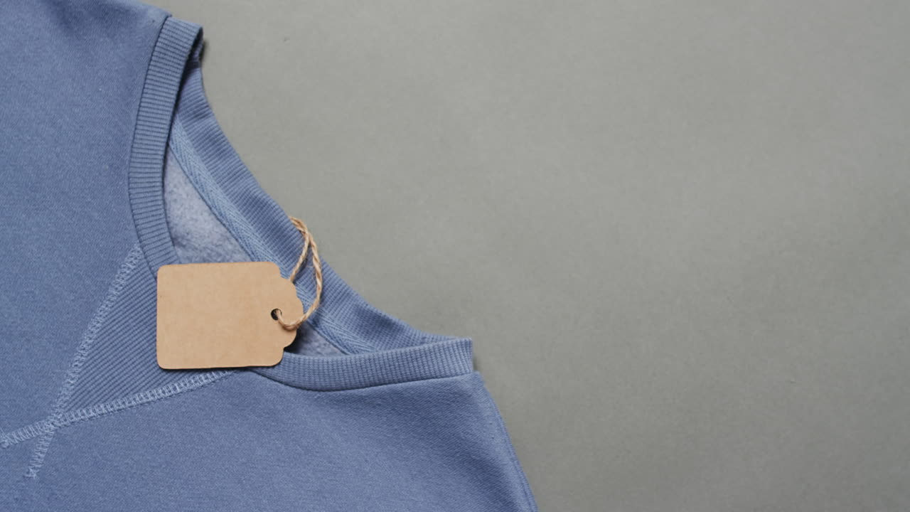 video di strato piatto di maglietta blu con tag e spazio di copia su sfondo grigio