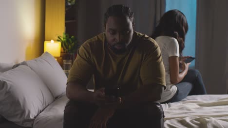 Couple-With-Relationship-Problems-At-Home-At-Night-Both-Looking-At-Mobile-Phones-In-Bedroom-9