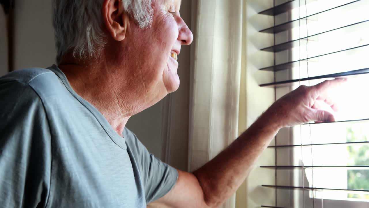 시니어 남자가 창문에서 손을 흔들고 있습니다.