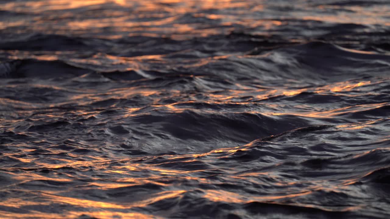 Ocean waves in evening at sunset with bright reflections