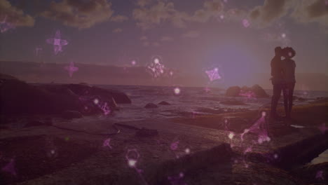 silhouetted couple embracing by ocean with glowing pink animation overlay