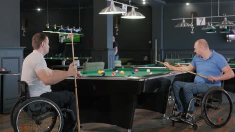 hombres adultos con discapacidad en silla de ruedas juegan al billar en el club