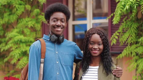 hombre y mujer afroamericanos mirando la cámara y sonriendo en la calle