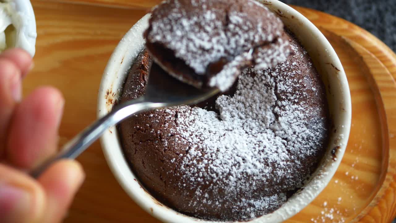 Close up of a chocolate lava cake with a spoon taking a bite