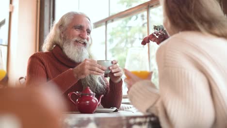 cheerful man talking to unrecognizable partner in cafe