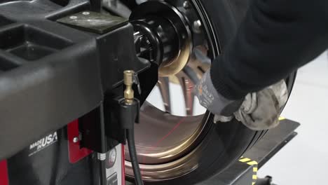 car mechanic fixing tire at repair shop, close up of a balancing machine