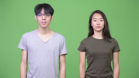 Young Asian couple pointing up