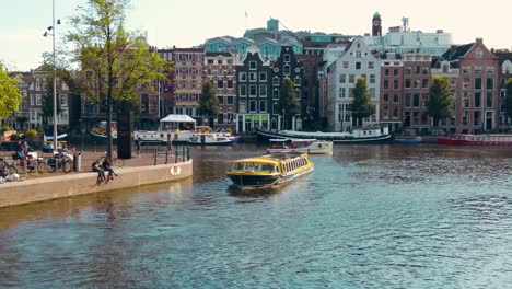 wide shot yellow tourist boat in amstel canal belt central of amsterdam summer