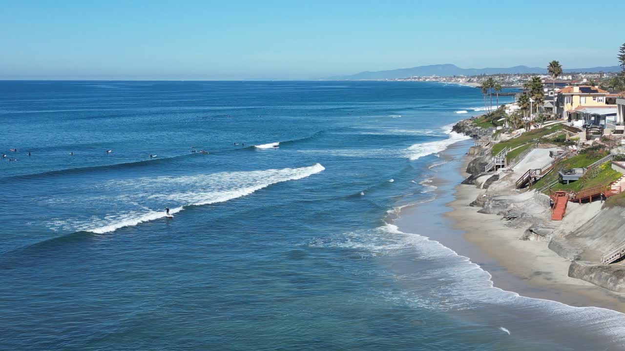 Ripresa con drone di surfisti che fanno surf in una splendida giornata invernale nella California meridionale, che mostra la spiaggia e il litorale
