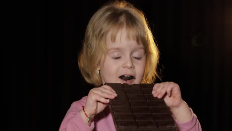 attractive child eating a huge block of chocolate. cute blonde girl