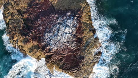 Top-down-ascending-shot-of-small-rock-Island-off-coast-of-Stradbroke-Island