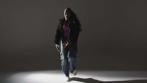 Full-Length-Studio-Portrait-Shot-Of-Young-Woman-Dancing-With-Low-Key-Lighting-Against-Grey-Background-4