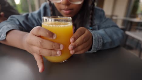 child holding glass of orange juice