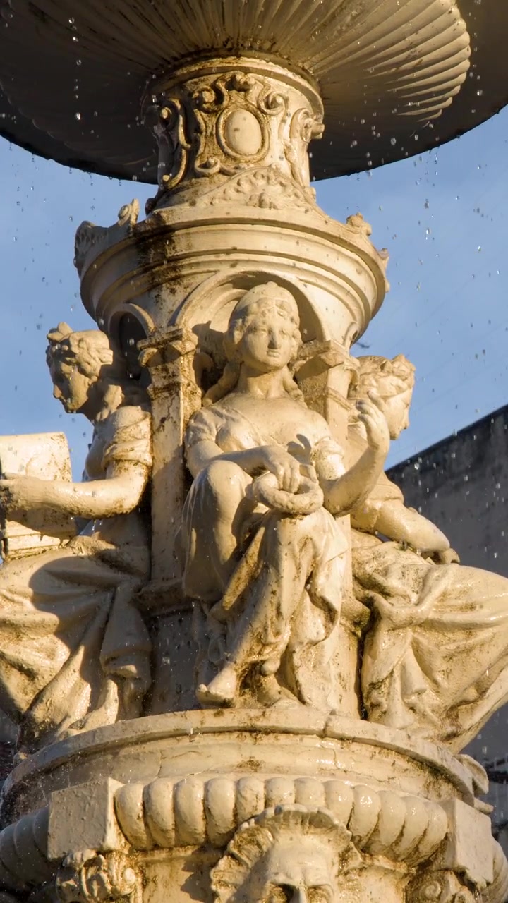 Un primo piano statico cattura le intricate sculture in pietra e l'acqua che scorre della Fontana Carriedo.