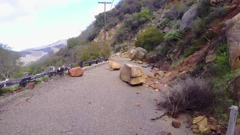 a landslide with large boulders blocks a road