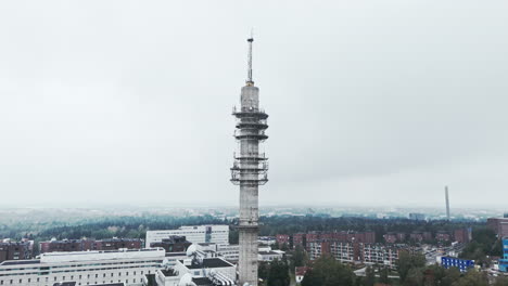 Aerial-shot-of-a-bleak-industrial-concrete-television-and-radio-link-tower-in-Pasila,-Helsinki,-Finland-on-a-bright-and-foggy-day