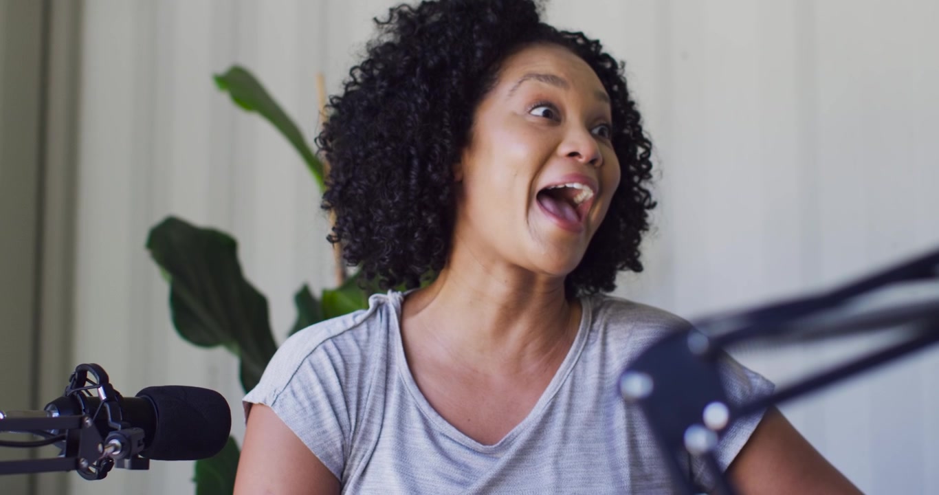 Donna afroamericana che risponde a una domanda fuori campo, parlando e gesticolando davanti a un microfono da tavolo.