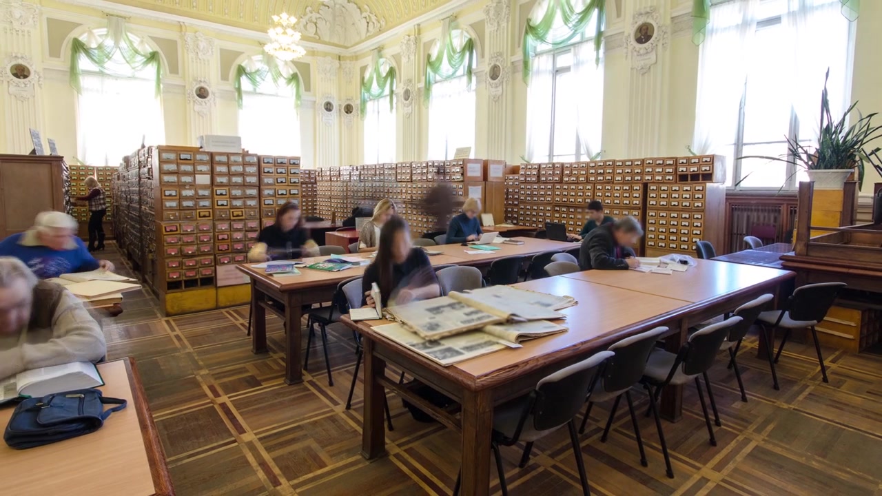 Persone che studiano nella sala lettura della biblioteca nazionale, timelapse. Libri e giornali su un tavolo.