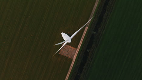 top view of propeller of a wind turbine generating renewable energy on the lush field in netherlands - aerial drone