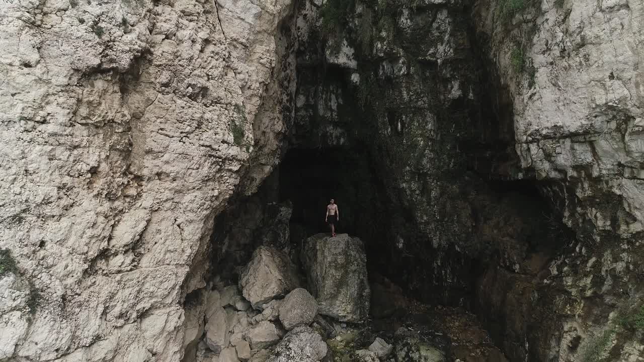 그림자 속에서 나와 다이빙을 위해 절벽을 기어오르는 남자의 공중 전경