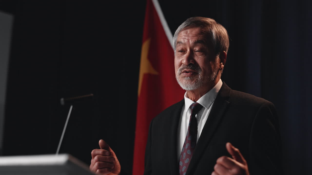 Man giving a speech at a podium with a flag in the background