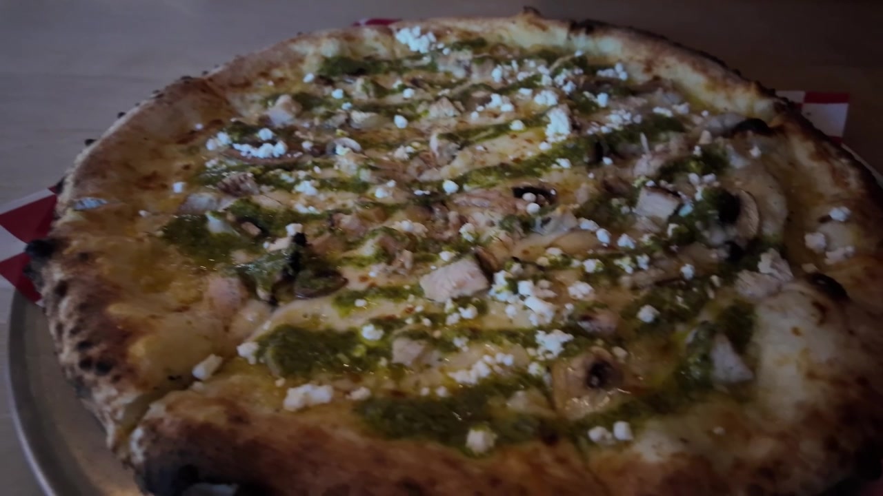 Una pizza condita con pollo, aglio e formaggio in una pizzeria